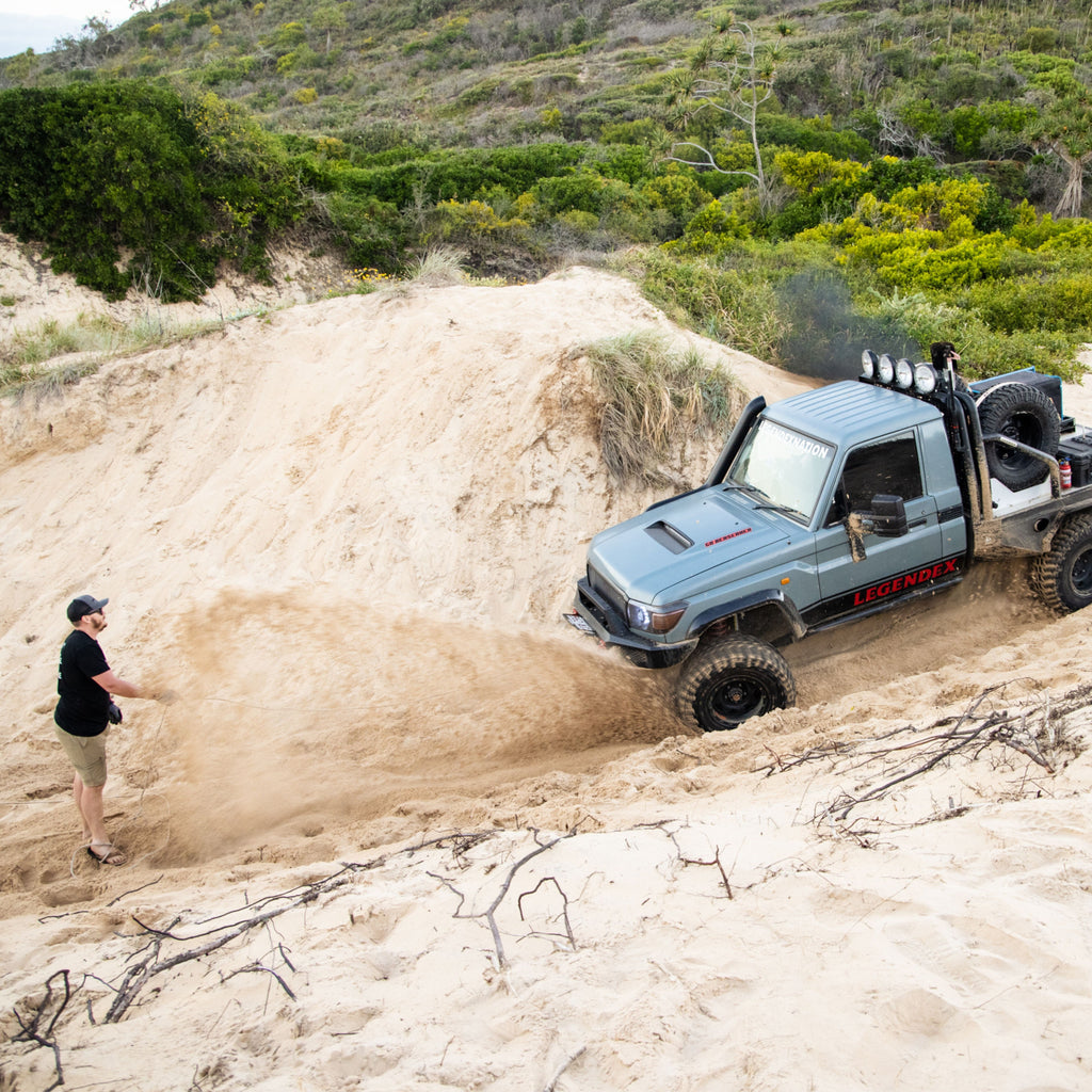 Vehicle bogged on sandy beach spinning wheels